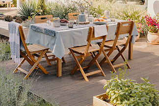 Das richtige Set für den Garten: Eine grosse Terrasse auf der ein grosser rechteckiger Gartentisch aus Holz mit fünf Holzstühlen steht.