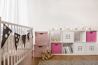Die richtige Aufbewahrung für mehr Ordnung: Ein Kinderzimmer, an dessen Wand eine weisse Kommode mit verschiedenen würfelförmigen Aufbewahrungsboxen in weiss und rosa steht.