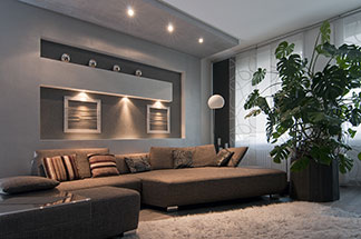 Die richtige Beleuchtung im Wohnzimmer: Verschiedene Lichtquellen sorgen in einem grossen Wohnzimmer mit einer braunen Sitzlandschaft für eine stimmungsvolle Atmosphäre.