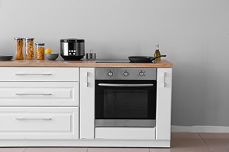 Perfekt integrierte Küchengeräte: Eine Küchenzeile in der ein Herd und ein Backofen integriert sind, steht vor einer grauen Wand.