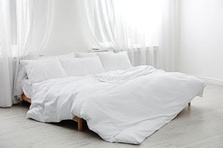 Die richtige Grösse zum Wohlfühlen: Helles Schlafzimmer mit einem Doppelbett auf dem eine grosse Bettdecke liegt.