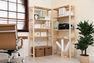 Aufbewahrung im Arbeitszimmer: Zwei offene, hohe Holzregale mit unterschiedlichen Ordnungsboxen darin stehen im Arbeitszimmer in der Wandecke.