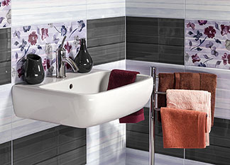 Ein Waschbecken mit geblümten, weissen und grauen Kacheln sorgt für wohnliches Ambiente im Badezimmer.