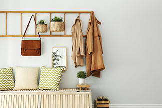 Die richtige Garderobe für den Flur: Ein schmaler Flurbereich mit Holzboden und weissen Wänden an dessen Ende ein weisser Garderobenschrank steht.