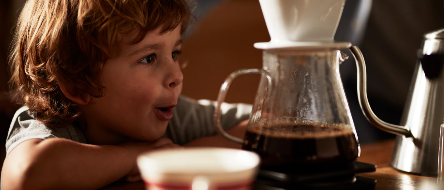 Ein Kind guckt einem Filterkaffee beim Brühen zu